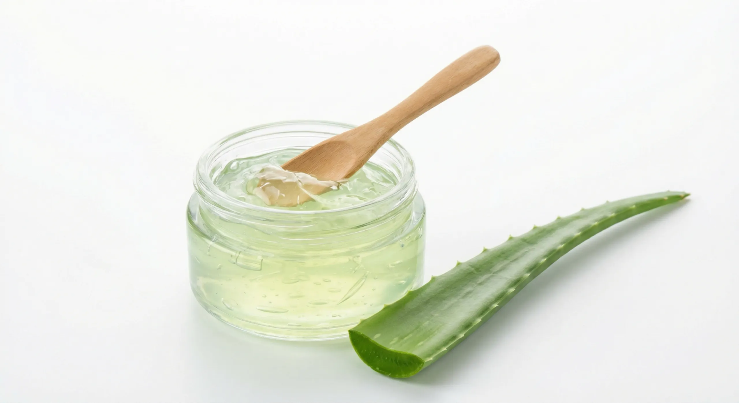 Čistý aloe vera gél v sklenenej nádobe s drevenou lyžicou