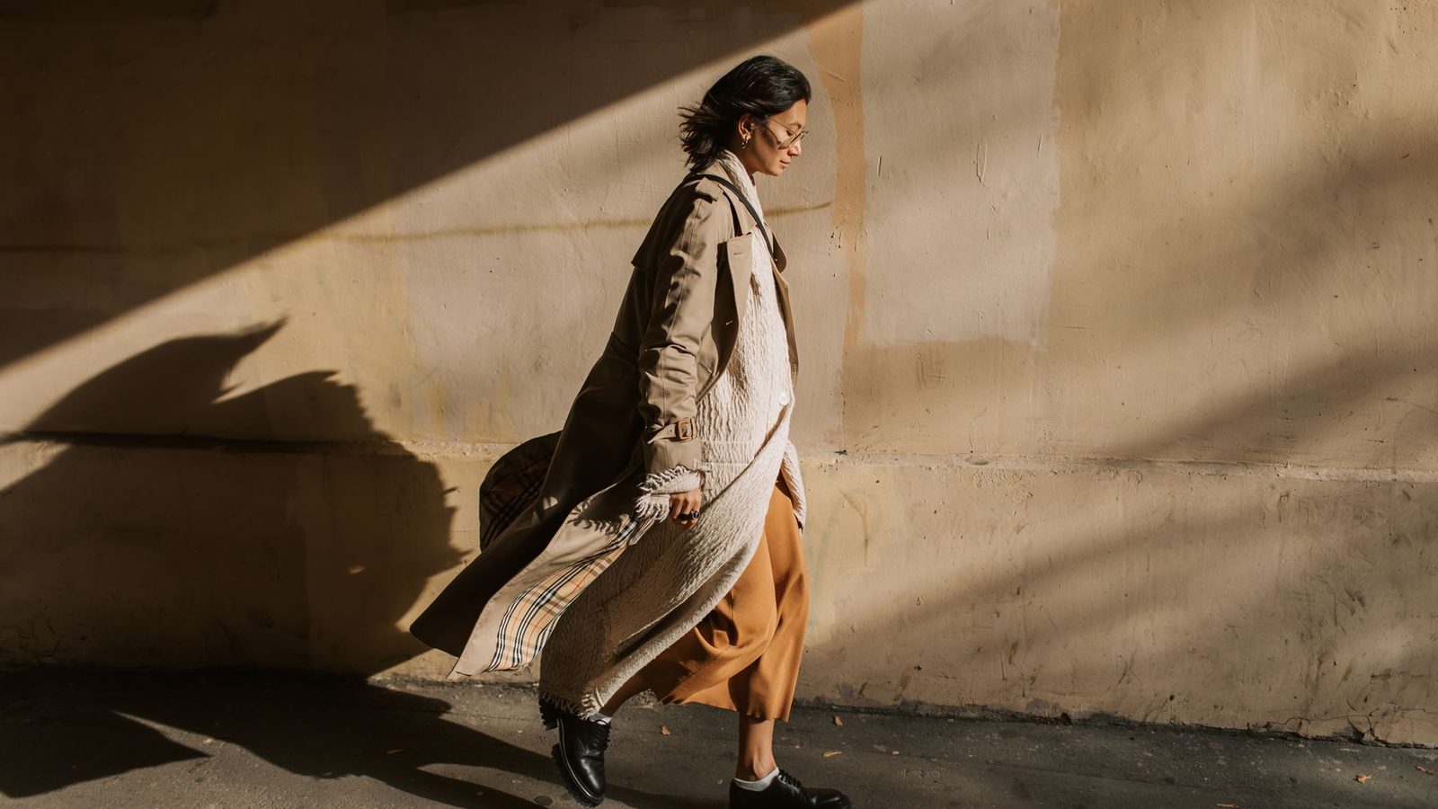 Žena v béžovom dámskom trenčkote kráča po ulici – street style